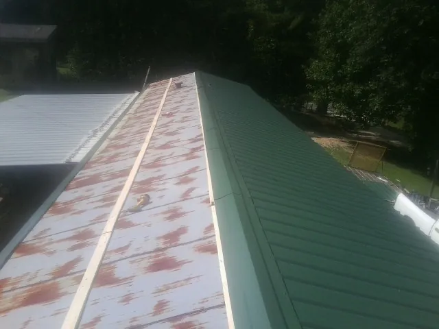 Old rusted panels beside newly installed green metal roofing — Wind Damage Roof Repair by Roofing Brothers in Glenn Dale