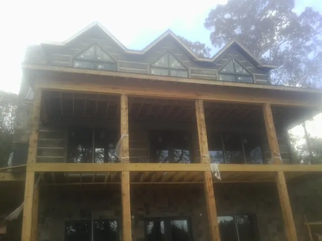 Dormers and porch framing on a large log home under construction — Roof Coating work by our crew in Glenn Dale