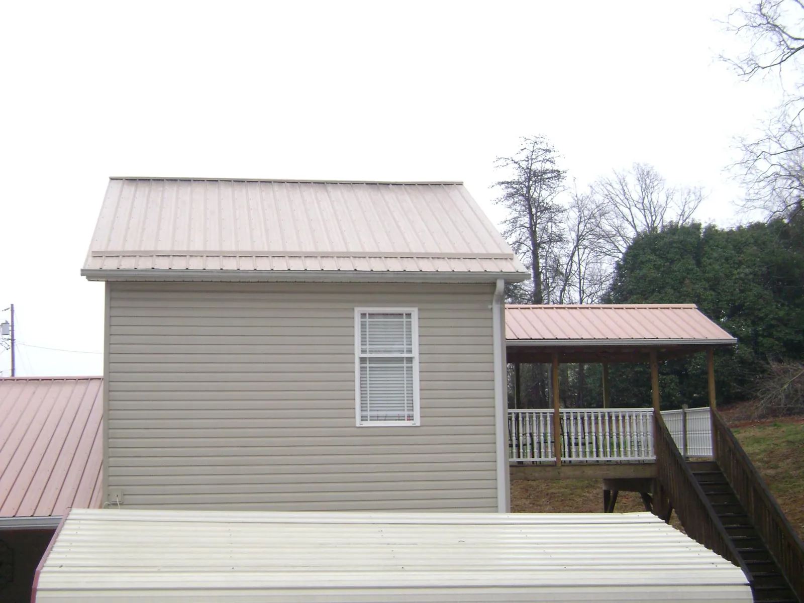 Tan metal roofs on a two story addition and attached porch, from a Roof Replacement job in Glenn Dale